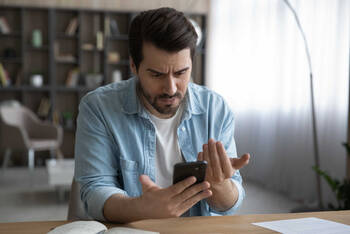 Man kijkt boos op zijn mobiele telefoon