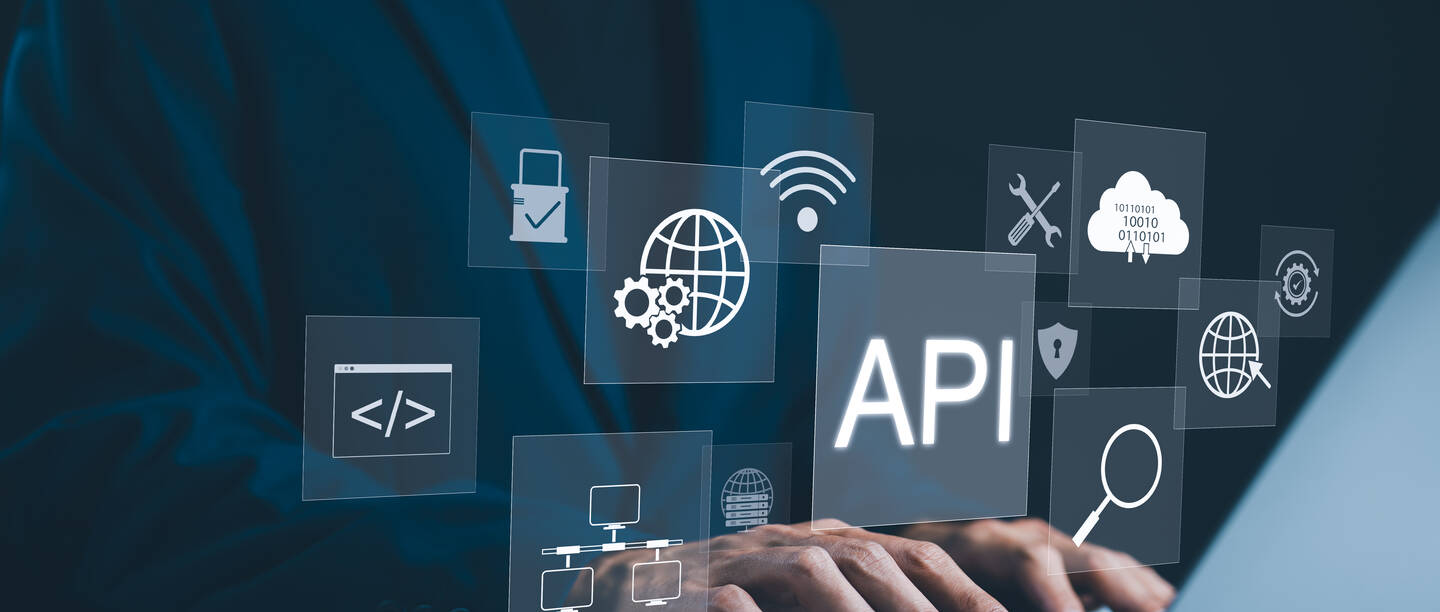 Een man zit achter zijn laptop. Je ziet technologische termen om hem heen - bijvoorbeeld API
