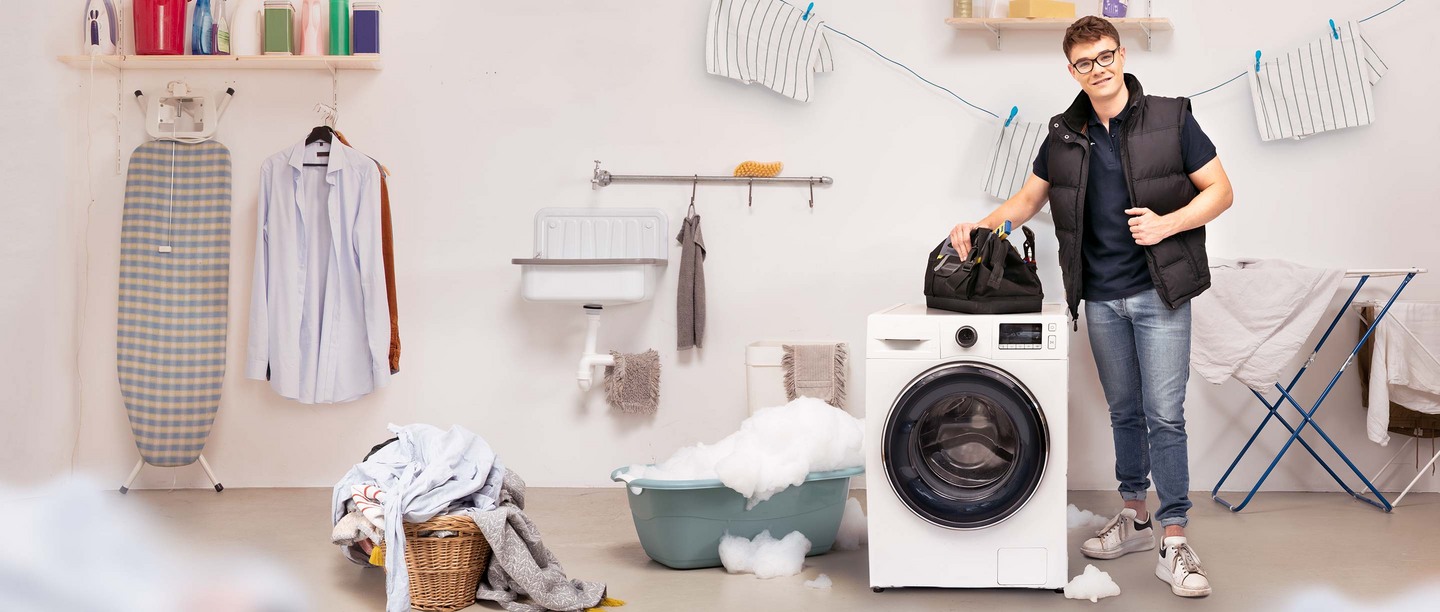 Een loodgieter staat voor een kapotte wasmachine
