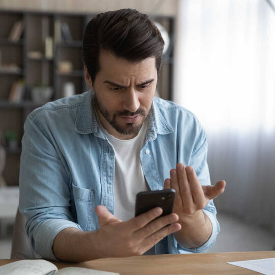 Man kijkt boos op zijn mobiele telefoon